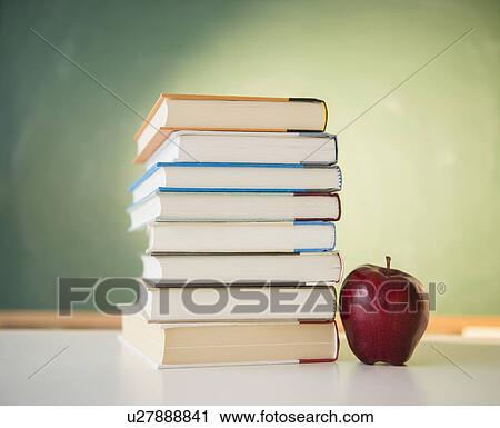 Stock Image - Studio Shot of books stacked and apple next to it. Fotosearch
