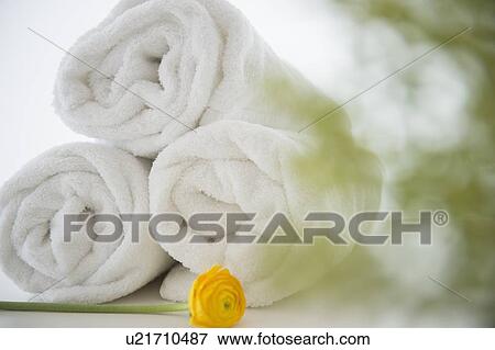 Stock Photo - Studio Shot of rolled up towels with yellow flower. Fotosearch
