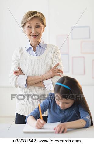 Stock Image - Teacher and schoolgirl (8-9) at school. Fotosearch