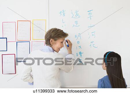Teacher and schoolgirl (8-9) writing at whiteboard View Large Photo Image Stock Image - Teacher and schoolgirl (8-9) writing at whiteboard. Fotosearch