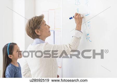 Teacher and schoolgirl (8-9) writing at whiteboard View Large Photo Image Stock Photo - Teacher and schoolgirl (8-9) writing at whiteboard. Fotosearch