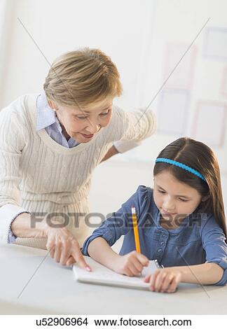 Teacher helping schoolgirl (8-9) at school View Large Photo Image Picture - Teacher helping schoolgirl (8-9) at school. Fotosearch