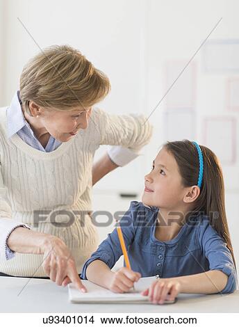 Picture - Teacher helping schoolgirl (8-9) at school. Fotosearch