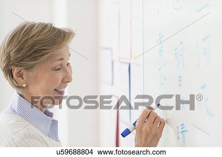 Picture - Teacher writing at whiteboard. Fotosearch