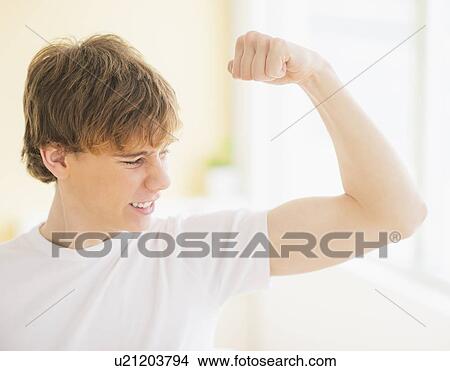 Picture - Teenage boy (14-15) flexing muscles. Fotosearch