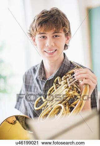 Teenage boy (14-15) in classroom holding french horn View Large Photo Image Stock Image - Teenage boy (14-15) in classroom holding french horn. Fotosearch