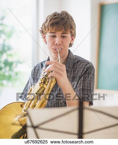 Teenage boy (14-15) in classroom playing french horn View Large Photo Image Stock Photography - Teenage boy (14-15) in classroom playing french horn. Fotosearch