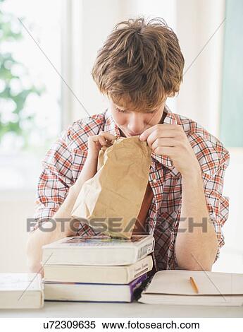 Teenage boy (14-15) looking inside paper bag View Large Photo Image Stock Photography - Teenage boy (14-15) looking inside paper bag. Fotosearch