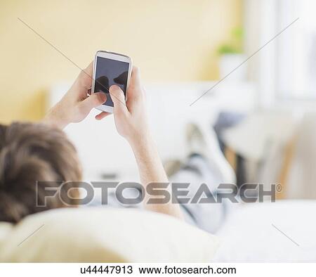 Teenage boy (14-15) lying on bed and text messaging View Large Photo Image Stock Image - Teenage boy (14-15) lying on bed and text messaging. Fotosearch
