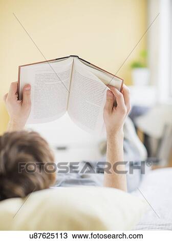 Teenage boy (14-15) lying on bed and reading book View Large Photo Image Stock Image - Teenage boy (14-15) lying on bed and reading book. Fotosearch
