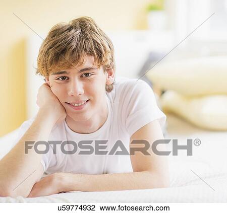 Teenage boy (14-15) lying on bed, Looking at camera View Large Photo Image Stock Image - Teenage boy (14-15) lying on bed, Looking at camera. Fotosearch
