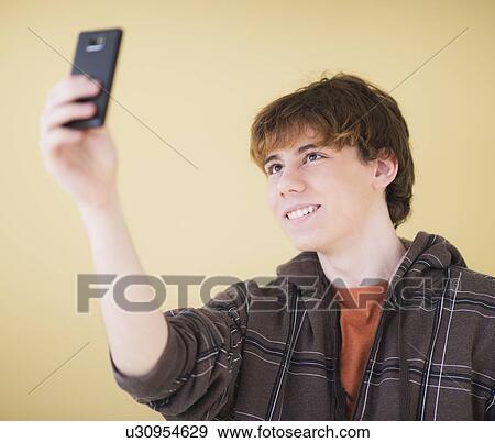 Stock Photo - Teenage boy (14-15) photographing himself with mobile phone. Fotosearch
