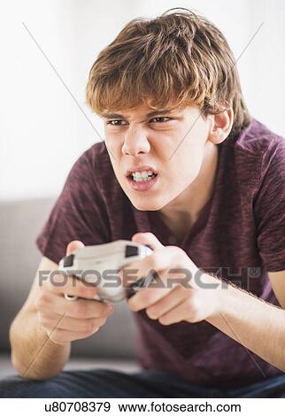 Stock Photo - Teenage boy (14-15) playing video game. Fotosearch
