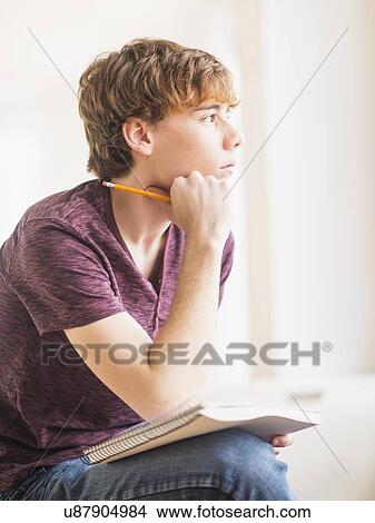 Teenage boy (14-15) sitting and holding pencil and note pad View Large Photo Image Picture - Teenage boy (14-15) sitting and holding pencil and note pad. Fotosearch