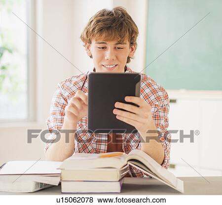 Stock Photo - Teenage boy (14-15) sitting in classroom with tablet pc. Fotosearch