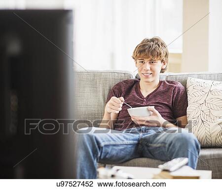 Teenage boy (14-15) watching tv and eating View Large Photo Image Stock Image - Teenage boy (14-15) watching tv and eating. Fotosearch