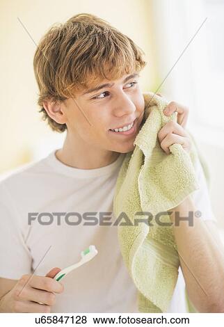 Stock Photo - Teenage boy (14-15) with toothbrush and towel. Fotosearch