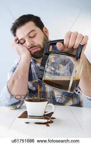 Tired, sleepy man spilling coffee on table View Large Photo Image Stock Photograph - Tired, sleepy man spilling coffee on table. Fotosearch