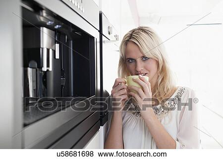 Stock Photo - Woman drinking coffee in kitchen. Fotosearch