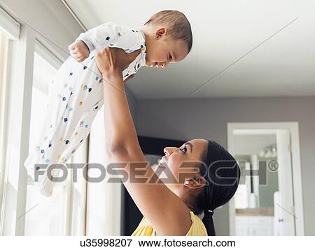 Woman holding up her baby son (2-5 months) View Large Photo Image Stock Photo - Woman holding up her baby son (2-5 months). Fotosearch