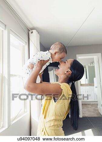 Stock Photo - Woman holding up her baby son (2-5 months). Fotosearch