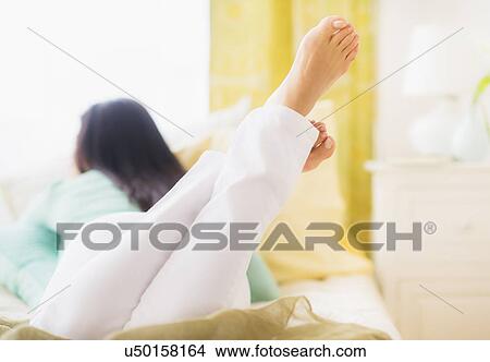 Woman lying down on bed View Large Photo Image Picture - Woman lying down on bed. Fotosearch