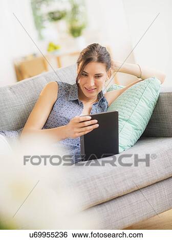 Woman using tablet pc on sofa View Large Photo Image Stock Photograph - Woman using tablet pc on sofa. Fotosearch