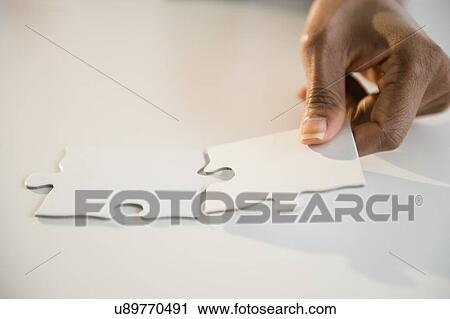Stock Image - Woman's hands matching jigsaw puzzle. Fotosearch