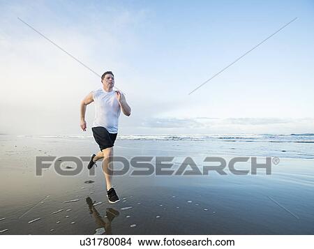 Young adult man running on beach View Large Photo Image Picture - Young adult man running on beach. Fotosearch