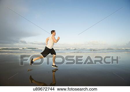 Young adult man running on beach View Large Photo Image Picture - Young adult man running on beach. Fotosearch