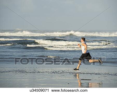 Young adult man running on beach View Large Photo Image Stock Image - Young adult man running on beach. Fotosearch
