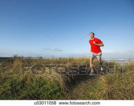 Young adult man running on dune View Large Photo Image Stock Photo - Young adult man running on dune. Fotosearch