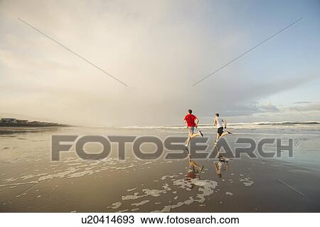 Young adult men running on beach View Large Photo Image Stock Image - Young adult men running on beach. Fotosearch