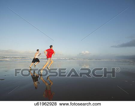 Young adult men running on beach View Large Photo Image Stock Photo - Young adult men running on beach. Fotosearch