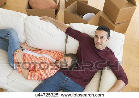 Young couple resting on sofa after moving into new home View Large Photo Image Stock Photography - Young couple resting on sofa after moving into new home. Fotosearch