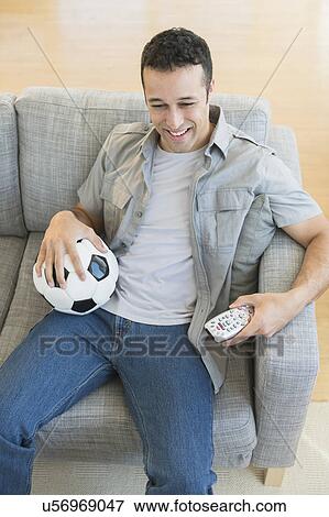 Stock Photo - Young man watching soccer match on tv. Fotosearch