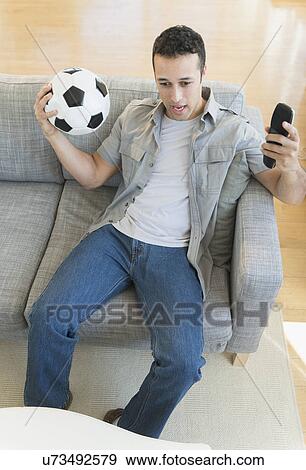 Stock Photo - Young man watching soccer match on tv. Fotosearch