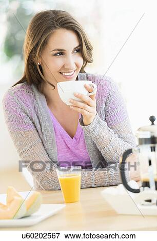 Young woman drinking tea at table View Large Photo Image Stock Photo - Young woman drinking tea at table. Fotosearch