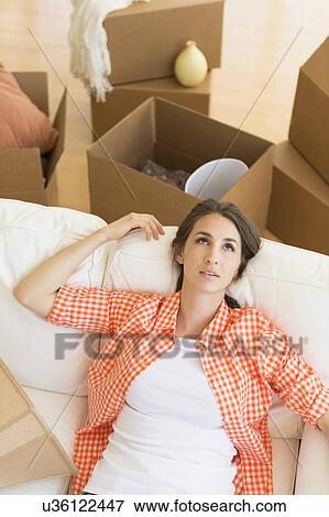 Young woman resting on sofa after moving into new home View Large Photo Image Stock Photo - Young woman resting on sofa after moving into new home. Fotosearch