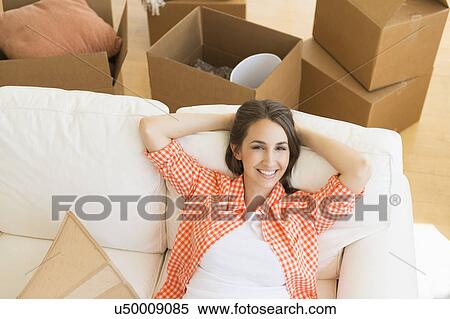 Stock Photography - Young woman resting on sofa after moving into new home. Fotosearch
