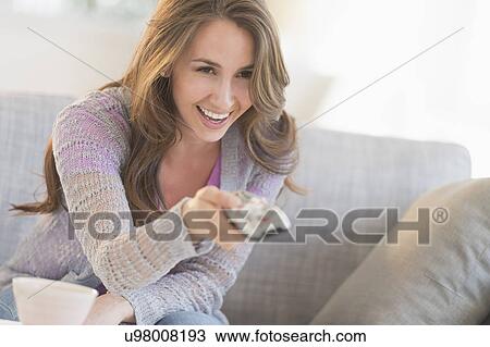 Young woman watching tv on sofa View Large Photo Image Stock Image - Young woman watching tv on sofa. Fotosearch