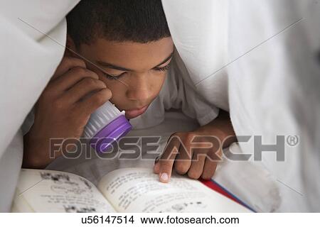 Picture - Boy Reading Book With Torch Under Duvet. Fotosearch