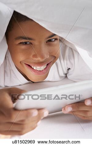 Boy Using Digital Tablet Under Duvet View Large Photo Image Stock Photo - Boy Using Digital Tablet Under Duvet. Fotosearch