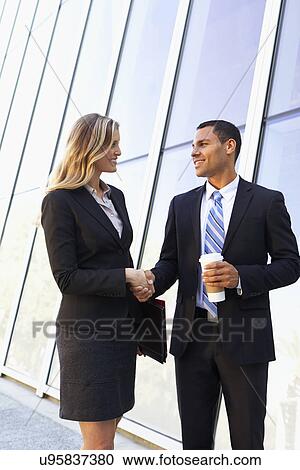 Stock Image - Businessman And Businesswomen Shaking Hands Outside Office. Fotosearch