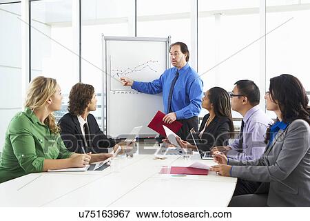Stock Photo - Businessman Conducting Meeting In Boardroom. Fotosearch