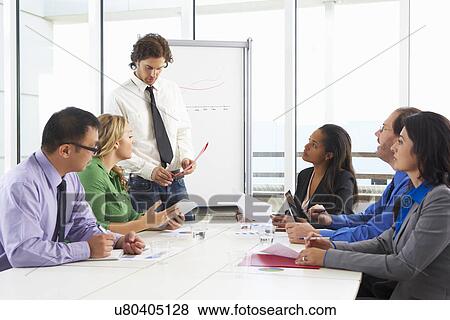 Stock Photo - Businessman Conducting Meeting In Boardroom. Fotosearch