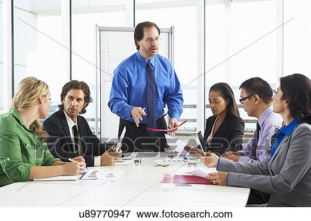 Stock Photo - Businessman Conducting Meeting In Boardroom. Fotosearch