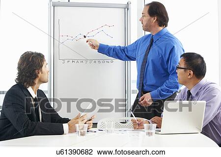 Stock Image - Businessman Giving Presentation To Colleagues. Fotosearch