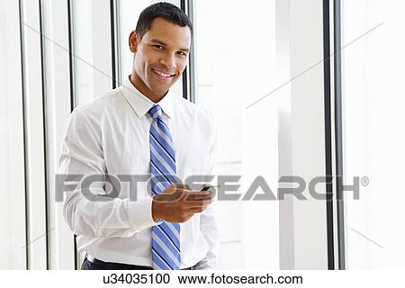 Businessman Using Mobile Phone In Office View Large Photo Image Stock Image - Businessman Using Mobile Phone In Office. Fotosearch