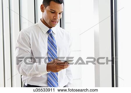 Stock Image - Businessman Using Mobile Phone In Office. Fotosearch